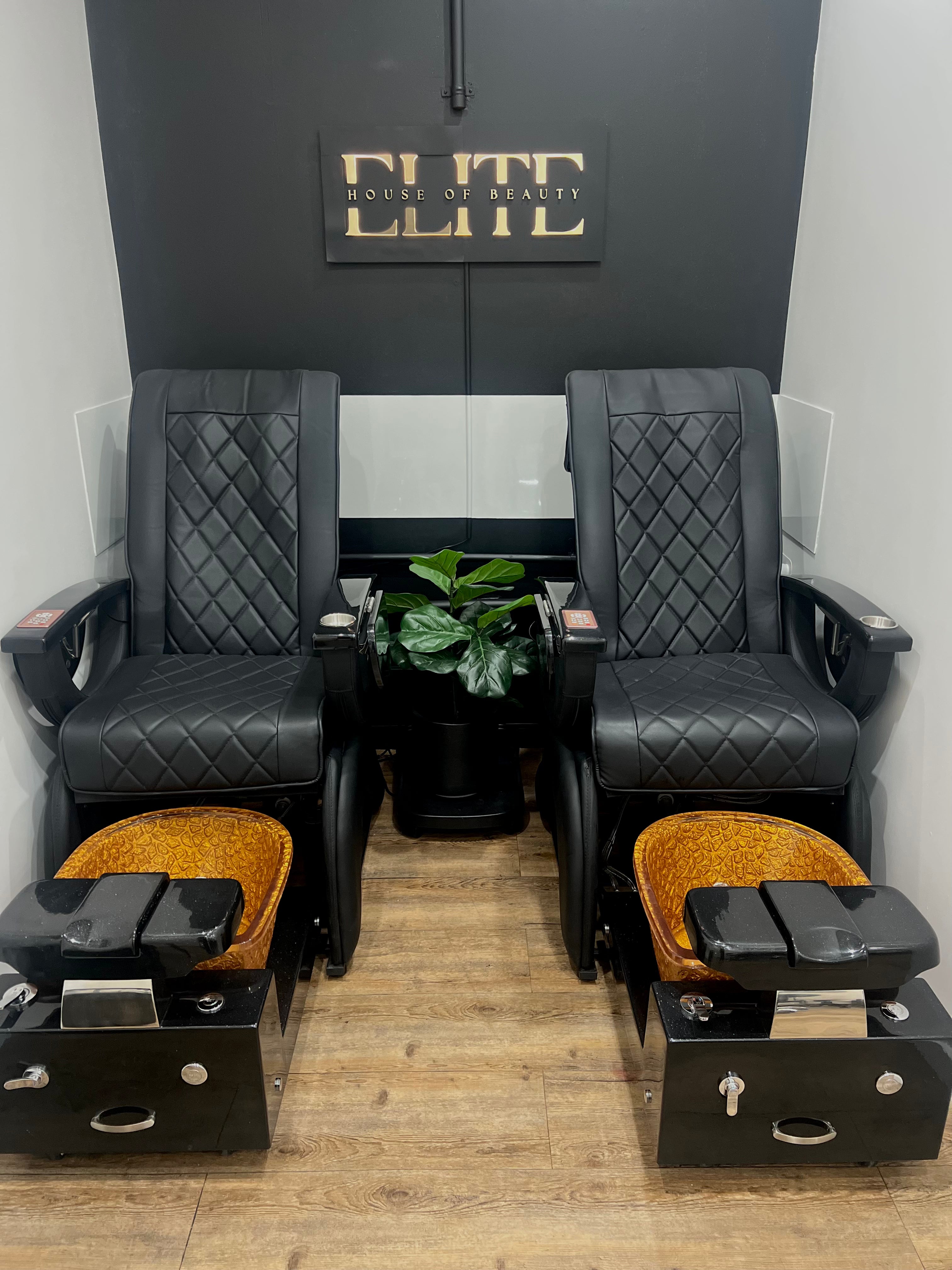 Two black pedicure chairs with foot wells in a salon setting, featuring the Elite House of Beauty sign.